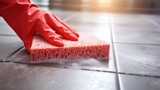 Cleaning floor tiles with sponge and rubber gloves.