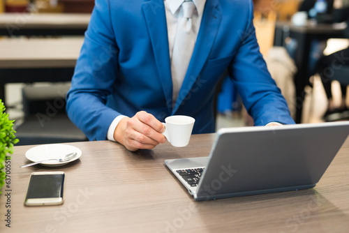 Businessman having breakfast while using his laptop