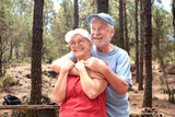 Happy senior couple hugging in the woods enjoying mountain hike appreciating nature and freedom, retired seniors man and woman and healthy lifestyle concept