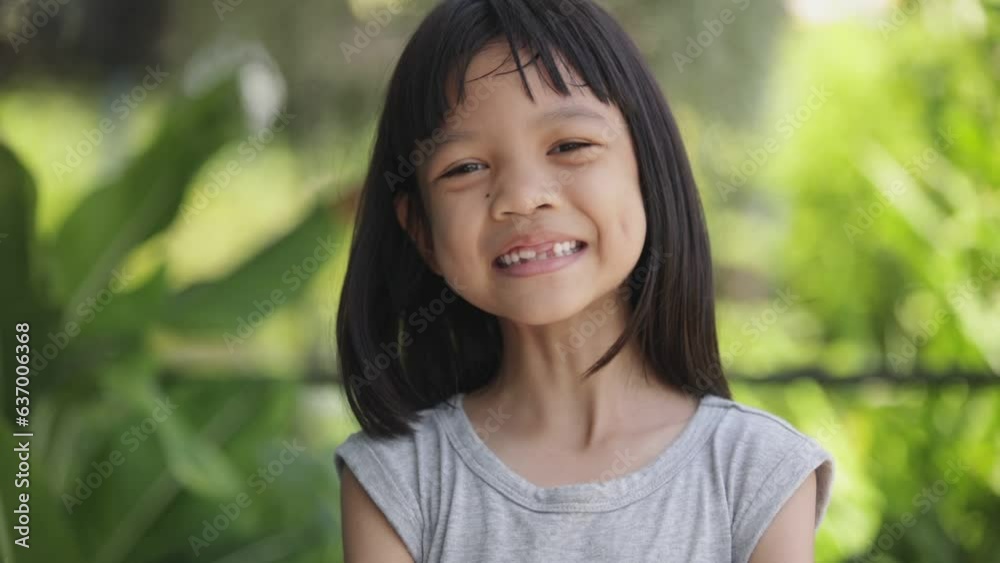 Close-up portrait of the bright face of Asian Thai kid girl aged 6 to 8 years, smiling beautifully, showing her growing teeth. She was a healthy and strong girl with beautiful long black hair. Close-up portrait of the bright face of Asian Thai kid girl aged 6 to 8 years, smiling beautifully, showing her growing teeth. She was a healthy and strong girl with beautiful long black hair.