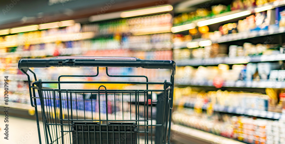 Shopping cart on the background of shop shelves in a supermarket Shopping cart on the background of shop shelves in a supermarket