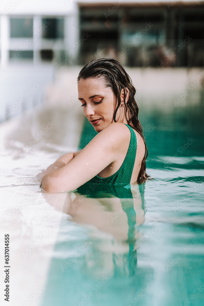 Chica joven delgada posando en piscina de hotel de vacaciones en traje de baño
