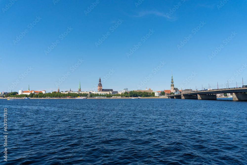 View of the Riga skyline from the other side of the Daugava river, on a sunny day.
