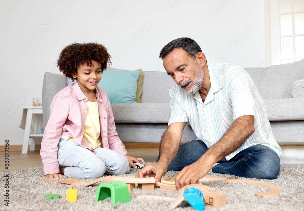 Smiling Hispanic Grandfather and Little Grandson Enjoying Toy Fun Indoors Smiling Hispanic Grandfather and Little Grandson Enjoying Toy Fun Indoors