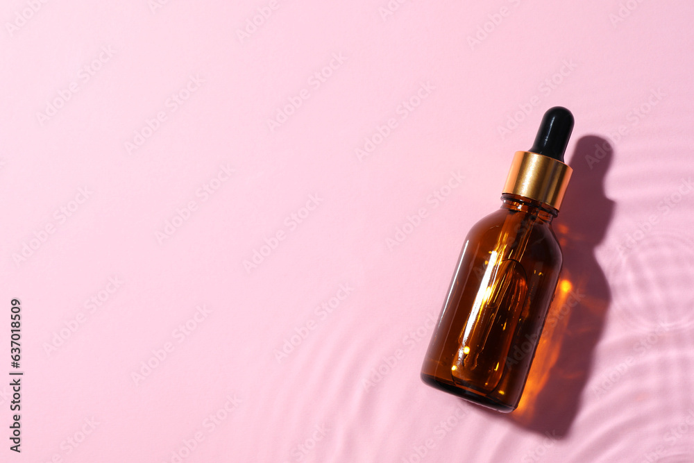 Bottle of cosmetic oil in water on pink background, top view. Space for text Bottle of cosmetic oil in water on pink background, top view. Space for text