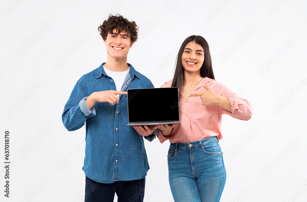 Cheerful Young Students Couple Showing Laptop Empty Screen, Studio Shot Cheerful Young Students Couple Showing Laptop Empty Screen, Studio Shot