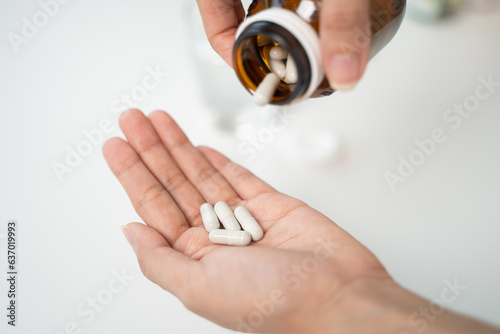 Tableau sur toile close up person pouring multivitamin capsules to her hands
