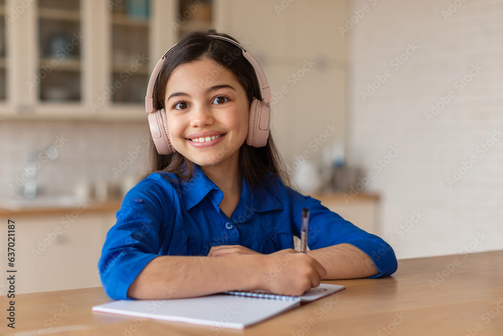 Happy School Girl Learning, Writing in Notebook Wearing Earphones Indoor Happy School Girl Learning, Writing in Notebook Wearing Earphones Indoor
