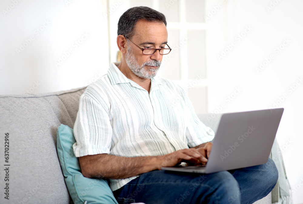 Hispanic Senior Man Using Laptop Computer Working Online At Home Hispanic Senior Man Using Laptop Computer Working Online At Home