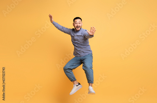 Cheerful Young Asian Man Fooling Over Yellow Background © Prostock-studio