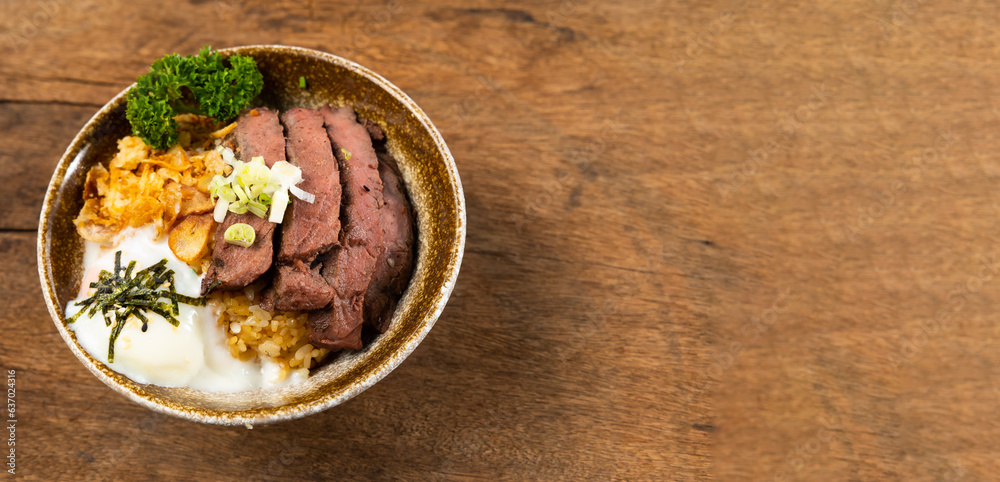 Beef Bowl. bowl of white rice topped with slices of grill beef. Japanese food on restaurant table. Isolate on wood background