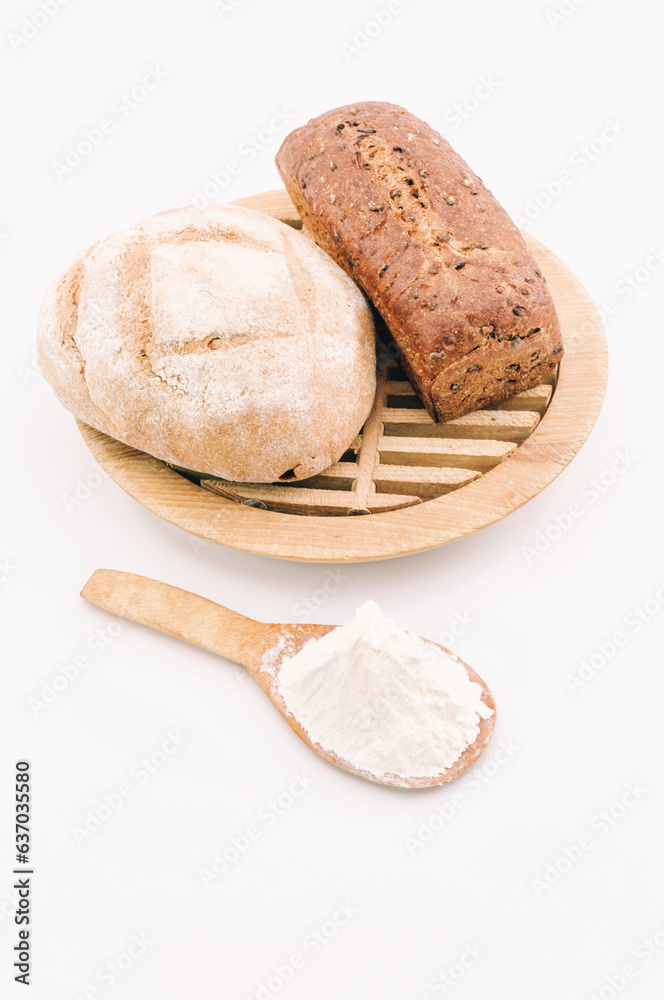 immagine primo piano di pagnotte artigianali di pane da farine di origine biologica, tagliere in legno e farina di grano duro su superficie bianca