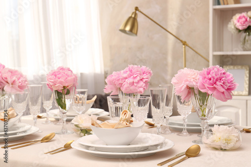 Stylish table setting with beautiful peonies and fabric napkins indoors © New Africa