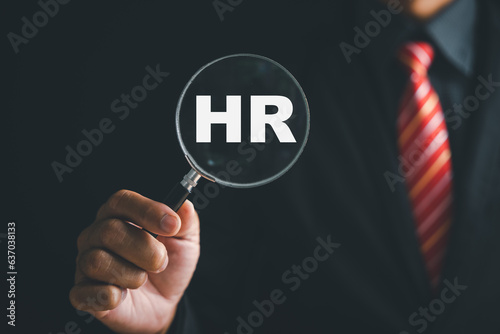 Unlocking HRM potential Magnifier glass highlights manager icon in staff icons, representing power of human resource management in recruitment, leadership, employee development. employees selection