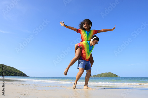 Lesbian woman on back ride with partner laughing in joy and happiness by the beach  lesbian  and a couple at the beach and piggyback ride for love  summer and vacation together for LGBTQ  travel  and 