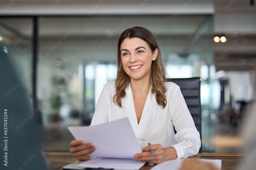 Smiling mature business woman hr holding cv at job interview. Happy mid aged professional banking financial manager, insurance agent, lawyer consulting clients sitting at work corporate office meeting Smiling mature business woman hr holding cv at job interview. Happy mid aged professional banking financial manager, insurance agent, lawyer consulting clients sitting at work corporate office meeting