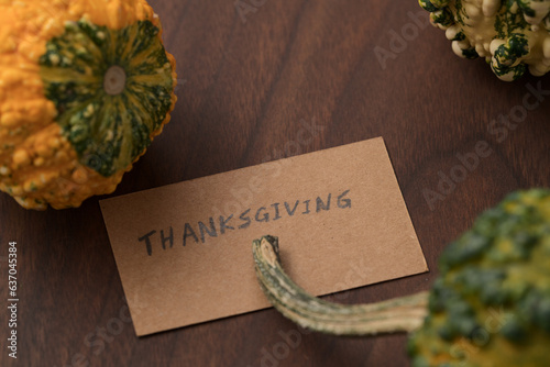 decorative pumpkins on walnut wood table with thanksgiving day paper card photo