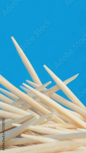 A pile of rotating wooden toothpicks on a blue background. Vertical video photo