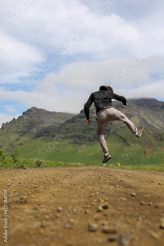 Un jeune touriste qui saute sur une chemin en Islande