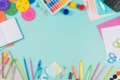 Back to school background. Colored pencils, markers, books, notebooks, pens, watercolor paint, scissors, math fractions, calculator on pastel green background. Top view, flat lay, copy space for text