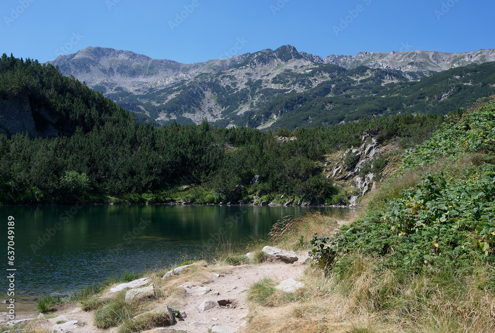 A calm mountain lake among the surrounding mountain peaks is covered by the bright rays of the sun. A calm mountain lake among the surrounding mountain peaks is covered by the bright rays of the sun.