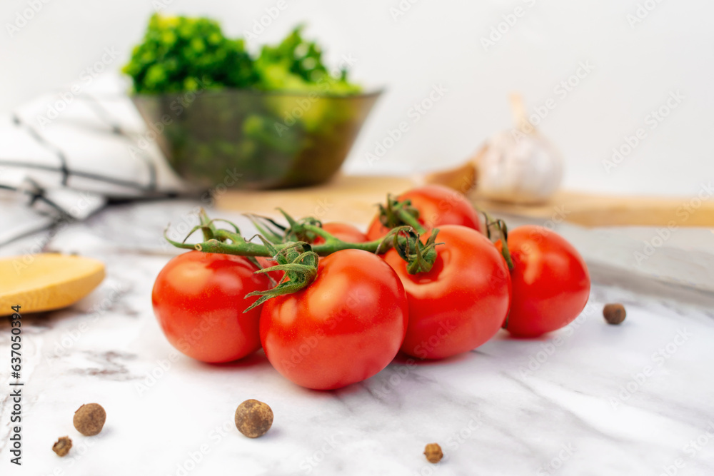 Branch of red ripe cherry tomatoes on the kitchen table. Bunch of fresh vegetables with green stems. Salad cooking, delicious food ingredient, harvest season. Branch of red ripe cherry tomatoes on the kitchen table. Bunch of fresh vegetables with green stems. Salad cooking, delicious food ingredient, harvest season.