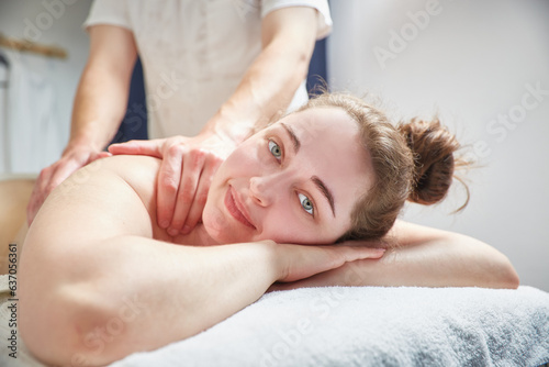 A beautiful girl looks into the camera during a back massage.