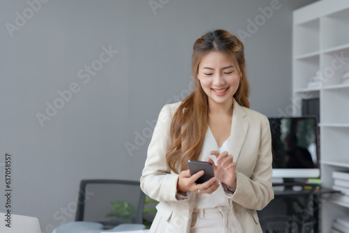 Beautiful charming asian businesswoman using mobile phone in the office. © amnaj