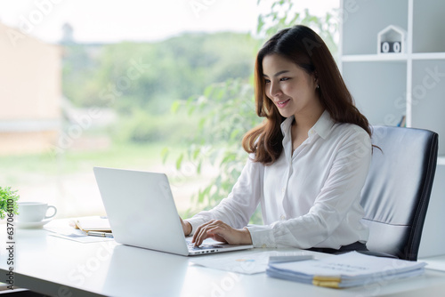 Asian Businesswoman sitting at her desk and busy working on a laptop in office