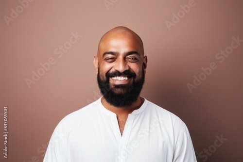 Medium shot portrait of an Indian man in his 40s against a minimalist or empty room background wearing hijab