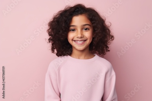 Portrait of a smiling little girl with curly hair on a pink background