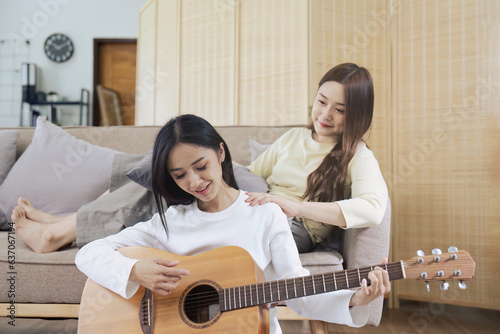 LGBTQIA lesbian gay couple playing guitar and singing with romantic feelings at home