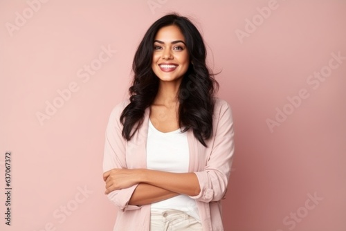 Portrait of a happy young woman standing with arms crossed against pink background