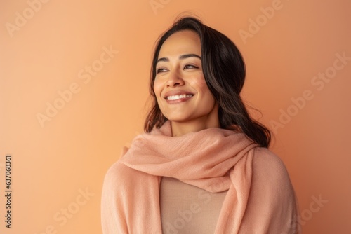 Portrait of a smiling young woman in a pink scarf on an orange background © Leon Waltz