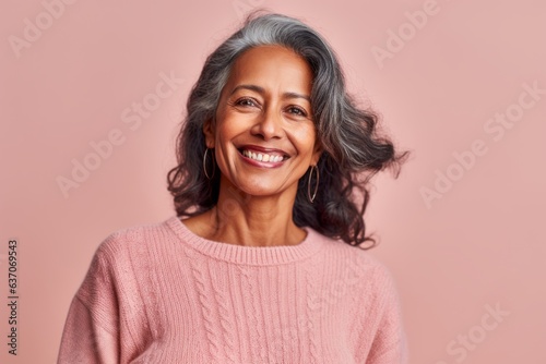 Portrait of a smiling mature woman with long grey hair on a pink background