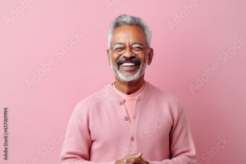 Portrait of an Indian asian senior man in pink sweater on a pink background.