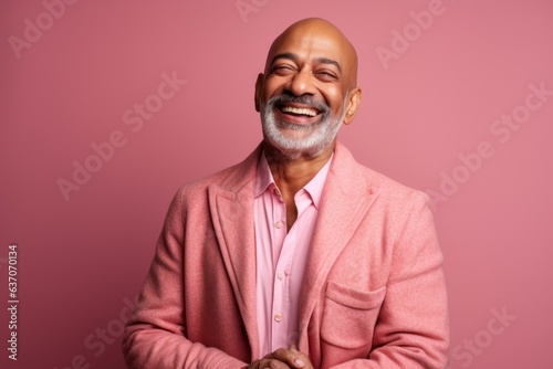 Portrait of a happy mature Indian man in a pink jacket.