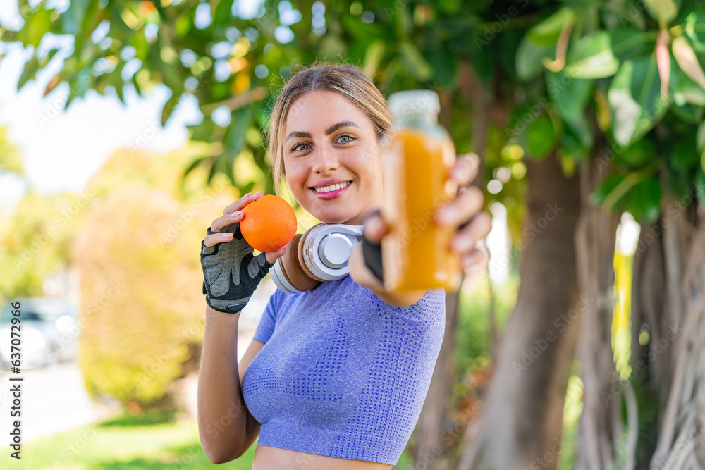 Young pretty sport woman at outdoors holding an orange and an orange juice Young pretty sport woman at outdoors holding an orange and an orange juice