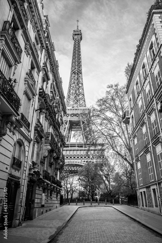 Fototapeta Naklejka Na Ścianę i Meble -  View of the Eiffel Tower from a nearby street full of residential buildings. Paris, France. Black and white photography.