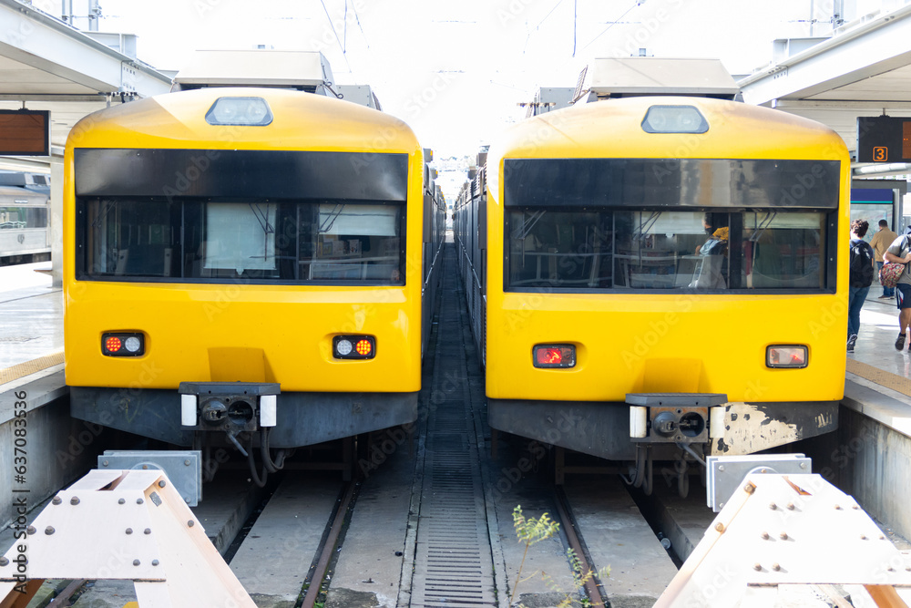 Two yellow trains stand on the tracks at the depot