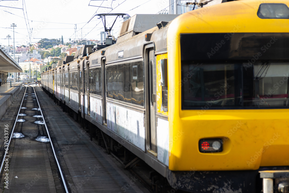 An electric train with yellow front cabin stands on the rails at the depot