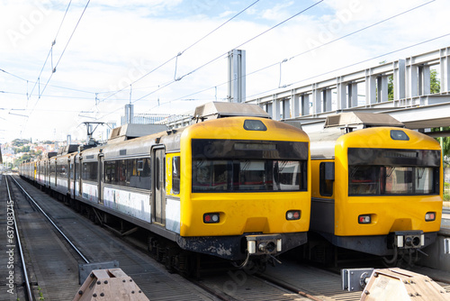 Two trains with yellow front cabins standing on the rails at the depot