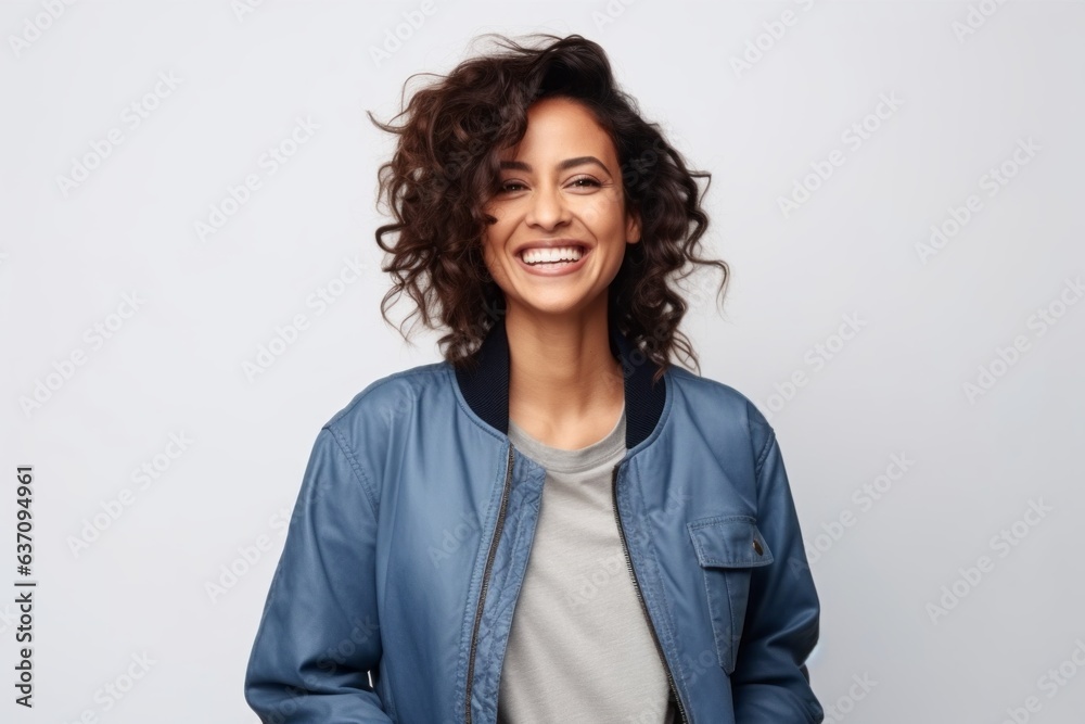 Medium shot portrait of an Indian woman in her 30s wearing a denim jacket against a white background Medium shot portrait of an Indian woman in her 30s wearing a denim jacket against a white background