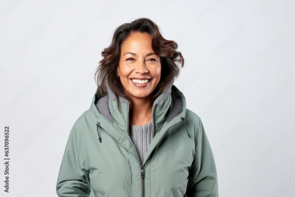 Medium shot portrait of an Indian woman in her 50s wearing a warm parka against a white background Medium shot portrait of an Indian woman in her 50s wearing a warm parka against a white background