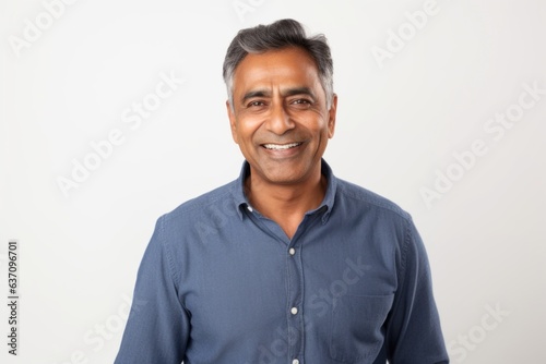 Medium shot portrait of an Indian man in his 50s against a white background