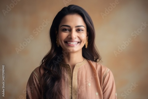 Close-up portrait of an Indian woman in her 30s wearing kurta pajama in a minimalist background
