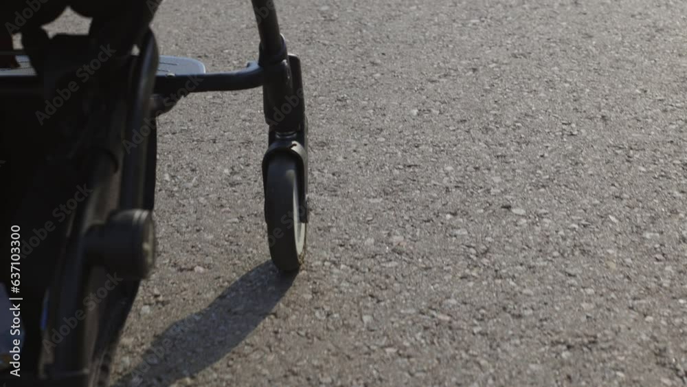 A child in a stroller. A girl is sitting in a cradle, her mother is pushing a cart. A walk with the baby in the fresh air. Gray stroller, motherhood, child care A child in a stroller. A girl is sitting in a cradle, her mother is pushing a cart. A walk with the baby in the fresh air. Gray stroller, motherhood, child care