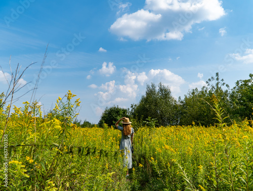 Young woman walking through yellow fields