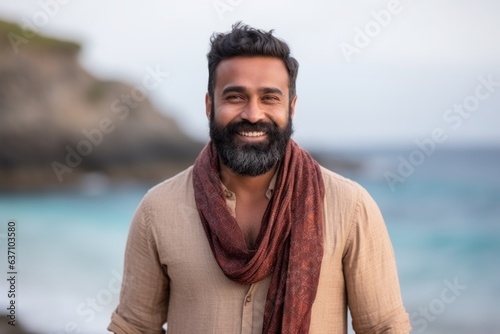 Medium shot portrait of an Indian man in his 30s wearing a foulard in a beach 