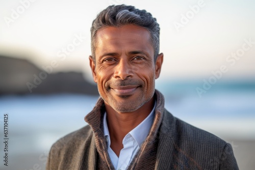 Portrait of handsome mature man smiling at camera on beach during sunset